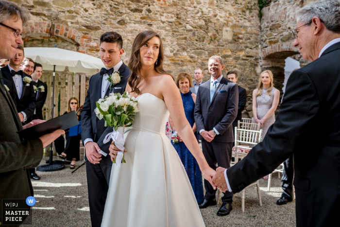 Foto: <a href="https://www.wpja.com/contests/2019-v07/best-wedding-photographers/2506906"> Annie Kheffache - Dun Laoghaire Dublin </a> Hochzeitszeremoniephotographie Wilton Castle, Irland, welche die Übergabe durch den Vater der Braut an den Bräutigam zeigt