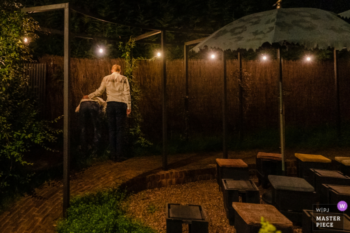 Photo by: <a href="https://www.wpja.com/contests/2019-v07/best-wedding-photographers/2507456">Simon Leclercq - Leuven Vlaams Brabant</a> A man supports his friend after he's had a little too much fun at La Petite Fabriek in this image composed by an award-winning Flanders wedding photographer.