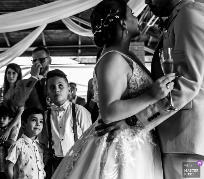 Foto: <a href="https://www.wpja.com/contests/2019-v07/best-wedding-photographers/2507906"> Victor R. Urosa - San Antonio de los Altos Miranda </a> Auf diesem dokumentarischen Schwarzweiß-Hochzeitsfoto, das von einem Fotografen aus Miranda, Venezuela, aufgenommen wurde, sehen die Gäste, wie Braut und Bräutigam in Caracas Champagner halten.