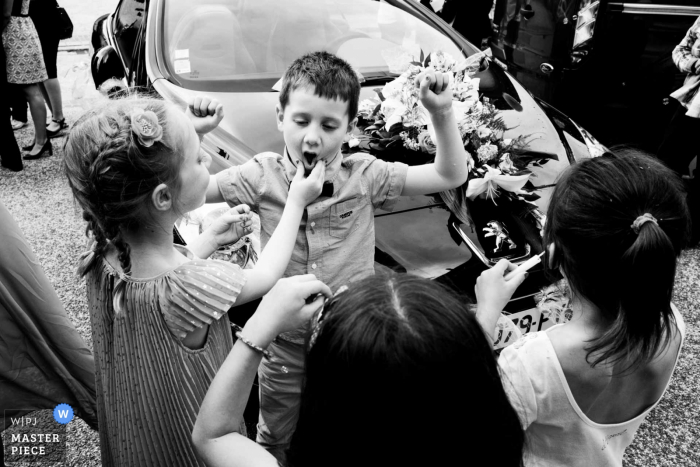 Children play around outside the Servolex Castle in this black and white wedding picture created by a Savoie wedding photographer. 