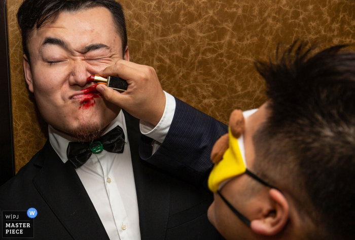 Um homem de olhos vendados tenta colocar batom vermelho em outro durante um jogo nesta foto por um fotógrafo de casamento de Pequim, China.