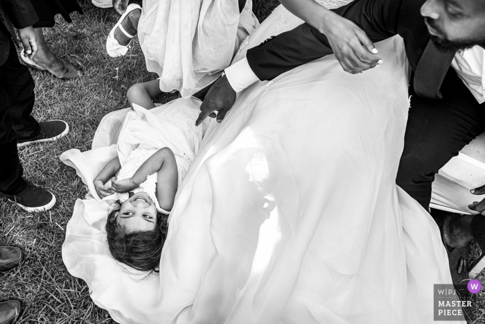 Foto von: <a href="https://www.wpja.com/contests/2019-v08/best-wedding-photographers/2512696"> Christophe Viseux - Toronto Ontario </a> Ein kleines Mädchen liegt im Zug der Braut in Addis Abeba in diesem Schwarzweißbild, das von einem preisgekrönten Hochzeitsfotografen aus Toronto, Ontario, erstellt wurde.
