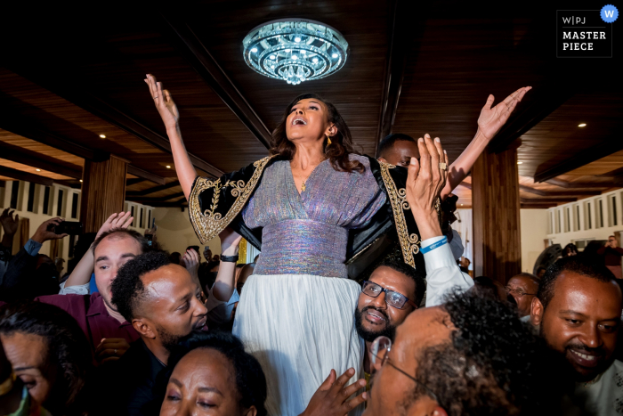 Guests lift up the bride during the reception at Addis Ababa in this photo by a Toronto, Ontario wedding photographer. 