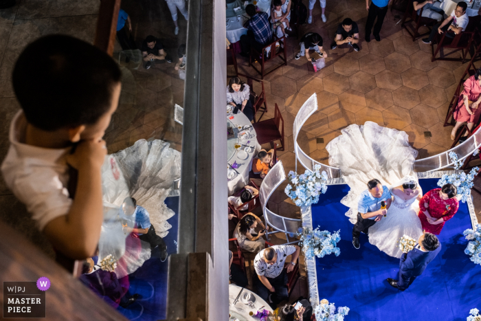 Photo by: <a href="https://www.wpja.com/contests/2019-v08/best-wedding-photographers/2515636">Zefan Tang - Changsha </a> A young boy watches the YueYang ceremony from above in this photo by a Hunan, China documentary wedding photographer.