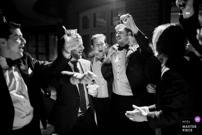 Photo by: <a href="https://www.wpja.com/contests/2019-v08/best-wedding-photographers/2516691">Ben Schaefer - Arlington Massachusetts</a> Vermont Inn wedding photo showing groom and groomsmen enjoying cigars