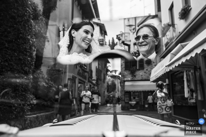 Photo by: <a href="https://www.wpja.com/contests/2019-v08/best-wedding-photographers/2518016">Daniele Borghello - Padova</a> Garda Island - Italy Wedding Photographer. On the way to the church by car. A smile between the bride and the father reflected in the mirror, among the streets of sirmione.