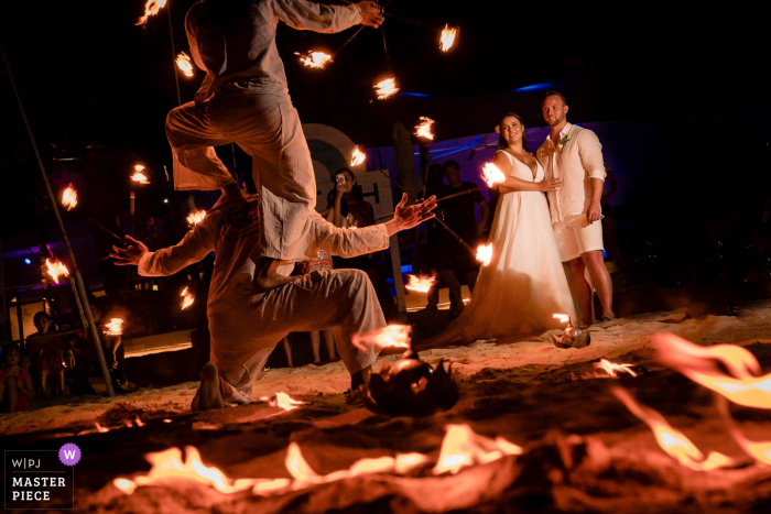 Photo by: <a href="https://www.wpja.com/contests/2019-v08/best-wedding-photographers/2518516">Stam Chananakhon - Phuket </a> The bride, groom, and guests enjoy a fire dance show at night in this documentary-style wedding image composed by a Phuket, Thailand photographer.