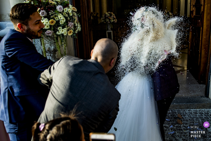 Photo by: <a href="https://www.wpja.com/contests/2019-v08/best-wedding-photographers/2518716">Pasquale Minniti - Reggio Calabria</a> The bride and groom are completely obscured by rice tossed at them by guests as they exit their Reggio Calabria ceremony in this photo by a documentary-style Calabria wedding photographer.