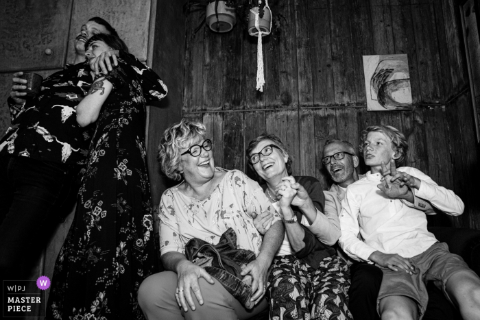 Photo by: <a href="https://www.wpja.com/contests/2019-v08/best-wedding-photographers/2520186">Nathalie Moors - Dessel Antwerpen</a> Guests sit on a bench and have a good time during the party at La Petite Fabriek in this black and white photo composed by an Antwerpen, Flanders wedding photographer.
