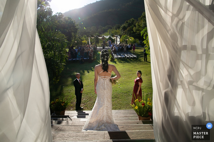Photo by: <a href="https://www.wpja.com/contests/2019-v08/best-wedding-photographers/2521081">Claudia Amorim - Goiânia </a> Guests watch as the bride descends the stairs at Estalagem Alter Real in Pirenópolis in this wedding photo captured by a Goias, Brazil documentary photographer.
