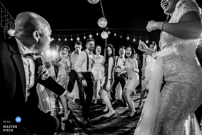 Photo by: <a href="https://www.wpja.com/contests/2019-v09/best-wedding-photographers/2531681">Huy Nguyen - Ho Chi Minh </a> Black and white wedding recepition image from Vietnam of the bride and groom with guests dancing.