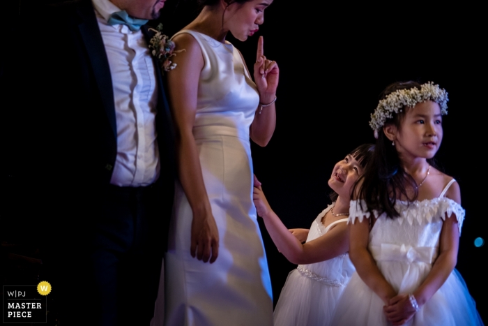 Photo de: <a href="https://www.wpja.com/contests/2019-v09/best-wedding-photographers/2532156"> Huy Nguyen - Hô Chi Minh </a> Une jeune fille se faisant dire par la mariée de se taire lors d'un discours lors d'un mariage à Nha Trang.