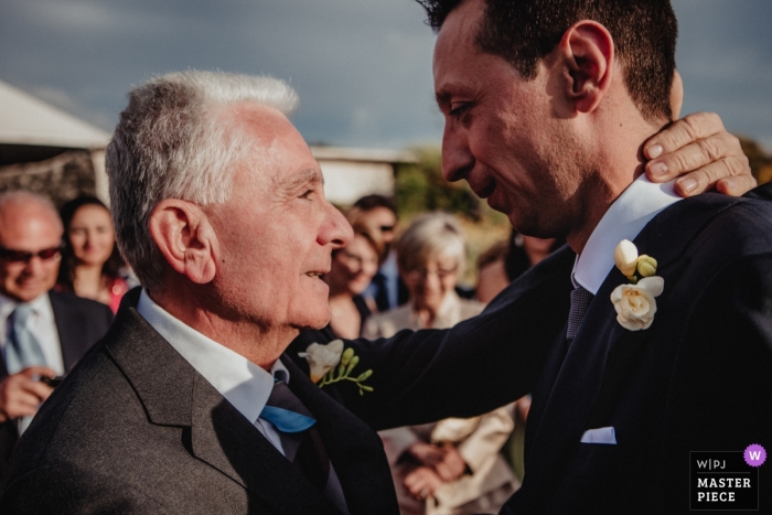 Photo by: <a href="https://www.wpja.com/contests/2019-v09/best-wedding-photographers/2532896">Mauro Santoro - Berlin Berlin</a> Wedding Photo of the father of the bride moved by congratulating the groom after the ceremony at Vulcano - Therasia Resort