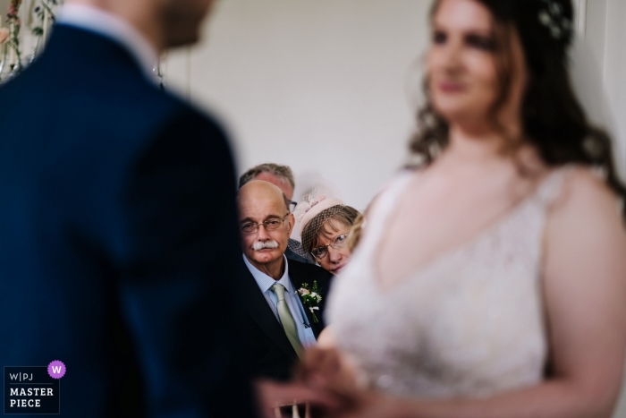 Photographie de la cérémonie de mariage de la maison Hestercombe - La mère de la mariée a du mal à se faire une bonne idée de l'échange de bague