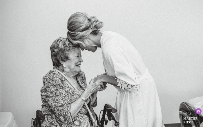 Photo by: <a href="https://www.wpja.com/contests/2019-v09/best-wedding-photographers/2539221">Andrea Bibeault - Omaha Nebraska</a> Scott Conference Center Wedding Reception Venue - Photo of the grandmother and bride holding hands
