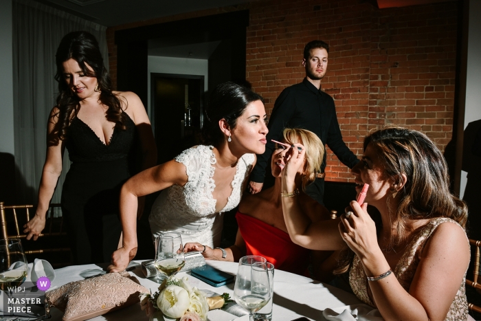 Photo by: <a href="https://www.wpja.com/contests/2019-v09/best-wedding-photographers/2539616">Adeline Leonti - Montreal Quebec</a> Place d'Armes Hotel, Montreal - Wedding photo of the maid of honor doing some quick touch ups on the bride during the reception