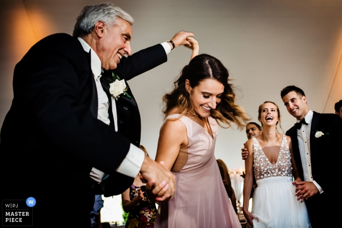 Foto: <a href="https://www.wpja.com/contests/2019-v09/best-wedding-photographers/2542041"> Jacob Hannah - Lincoln Vermont </a> Vermont-Hochzeitsfotos - Der Bräutigamvati und die Schwester tanzen, während die Braut und der Bräutigam während des Empfangs in Hildene, Manchester zuschauen