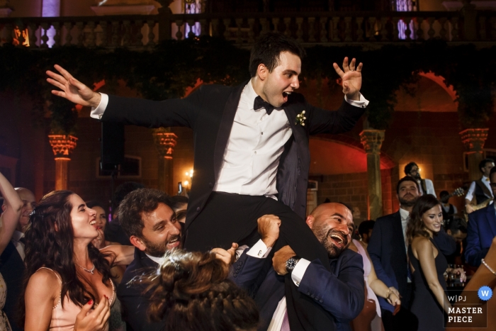 Foto do casamento do noivo que está sendo levantado no salão de baile durante uma recepção no palácio de Sursock em Beirute.