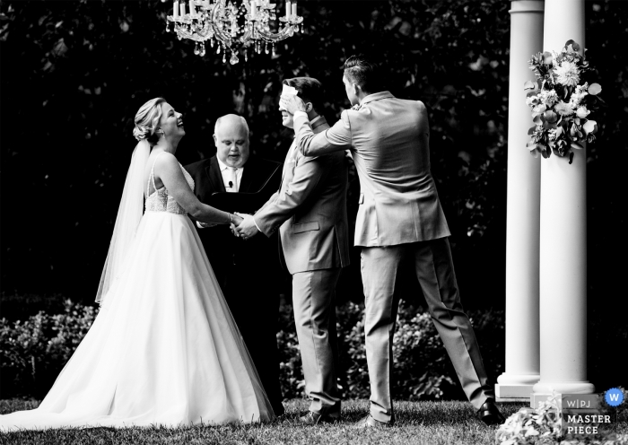 Photo by: <a href="https://www.wpja.com/contests/2019-v10/best-wedding-photographers/2543742">James Nix - Charlotte North Carolina</a> Best man wipes some sweat from his brow during the middle of a hot summer wedding ceremony at Separk Mansion.
