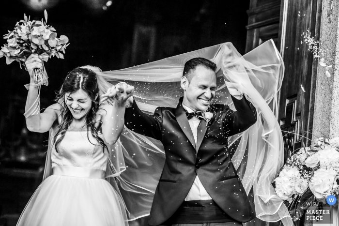 Photo by: <a href="https://www.wpja.com/contests/2019-v11/best-wedding-photographers/2544677">Luigi Rota - Lake Como Lecco</a> Black and white image of a bride and groom exiting Chiesa di San Giorgio as their guest shower them.