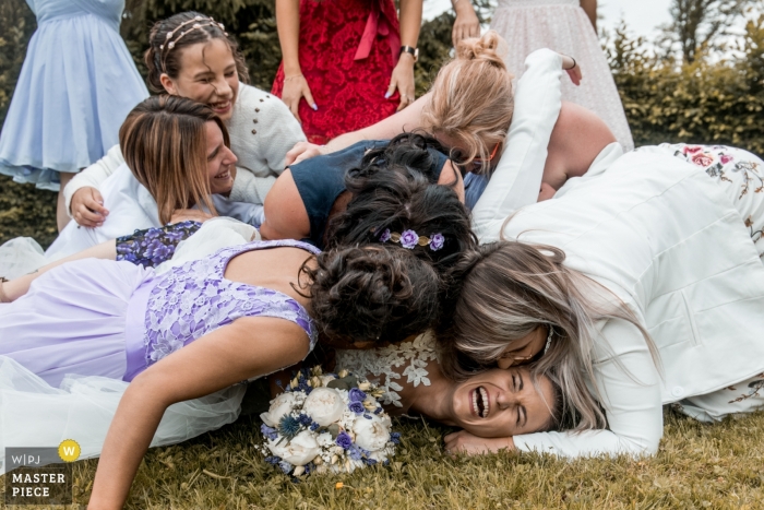 Photo by: <a href="https://www.wpja.com/contests/2019-v11/best-wedding-photographers/2544746">Cedric Derbaise - Bury </a> Ferme du Roy - France Wedding Photos of the bride being hugged on the ground by many girlfriends