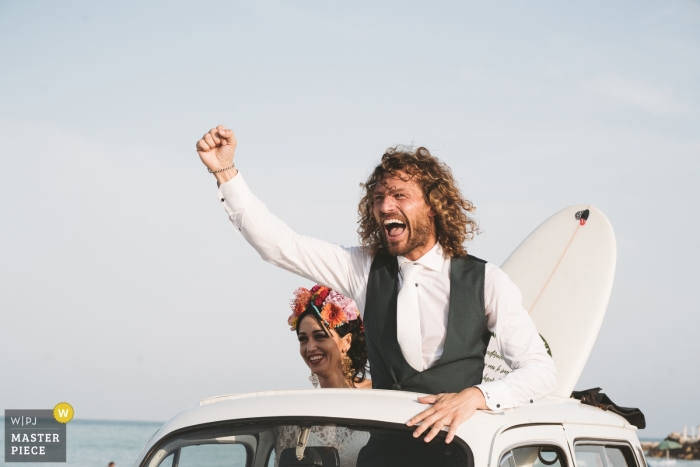 Zdjęcie: <a href="https://www.wpja.com/contests/2019-v11/best-wedding-photographers/2545137"> Sabrina Vinci - Civitanova Marche Macerata </a> Lungomare, porto sant'elpidio - Happy Groom w dachu samochodu ze swoją narzeczoną i deską surfingową!