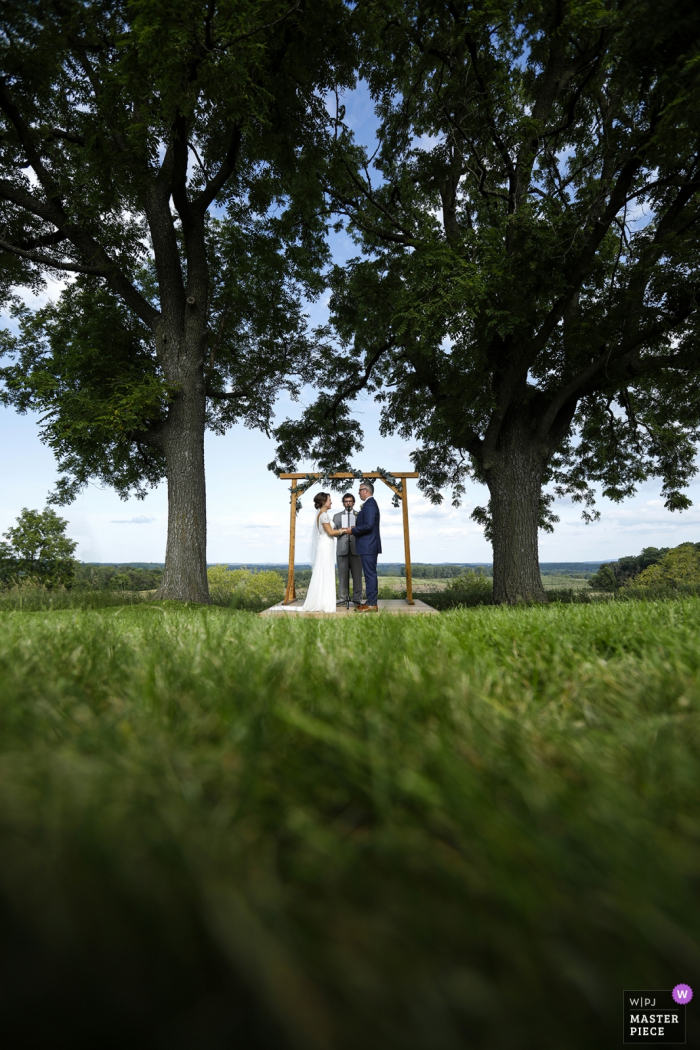 Photo by: <a href="https://www.wpja.com/contests/2019-v11/best-wedding-photographers/2545207">Ruthie Hauge - McFarland Wisconsin</a> Photographer for weddings at Vennebu Hill, Wisconsin Dells, WI | The bride and groom join hands as they are married on a hill overlooking the Wisconsin River valley.