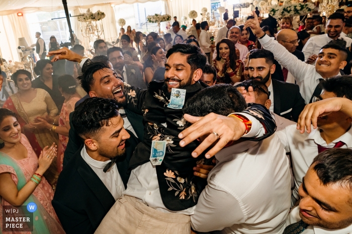 Photo by: <a href="https://www.wpja.com/contests/2019-v11/best-wedding-photographers/2545463">Rohit Gautam - Bedford Bedfordshire</a> Lakeview Marquee, London Wedding Reportage Photography of Groom jumped on his friends during dance