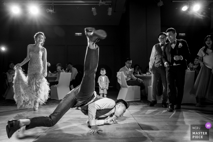 Photo by: <a href="https://www.wpja.com/contests/2019-v11/best-wedding-photographers/2545643">Will Tee - Taipei City </a> Wedding Dance Photos at Le Méridien Taipei - A groomsman was dancing on the dance floor, both the bride and the groom were watching him dancing . There was a little boy just keep staring at the groomsman's moves with all the attention.