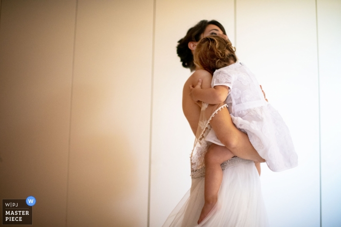 Photo by: <a href="https://www.wpja.com/contests/2019-v11/best-wedding-photographers/2546165">Maurizio Gjivovich - Ivrea Torino</a> Chiesa di Santo Stefano Chiaverano Ivrea TO / Location Cascina Laiasso Zimone BI - Photo of a hug between the spouse mother and her daughter enduring the preparation