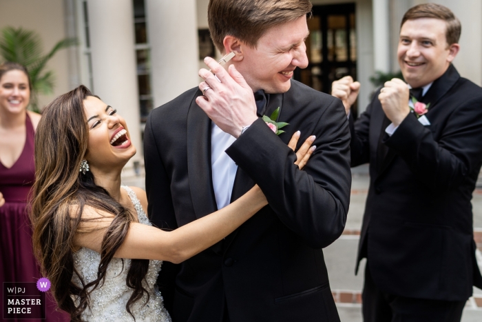 a clothespin on her grooms ear getting everyone a good laugh Biltmore Ballrooms Atlanta Wedding Venue Photography - Bride sneaks a clothespin on her grooms ear getting everyone a good laugh