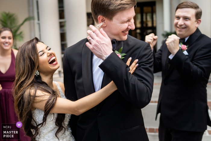 Biltmore Ballrooms Atlanta Hochzeitsfotografie - Die Braut schleicht sich eine Wäscheklammer ans Ohr ihres Bräutigams, um alle zum Lachen zu bringen