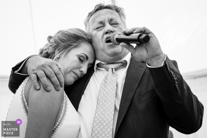 Father of the bride sings a song for his daughter while she seeks comfort in his arms at the Golf Club of Mean 