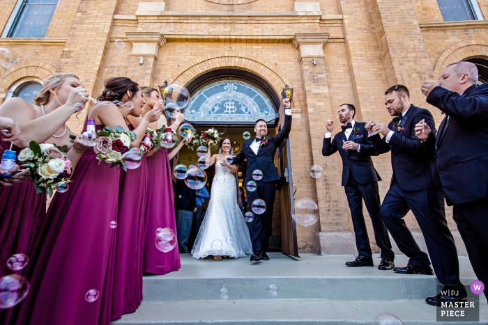 Zdjęcie: <a href="https://www.wpja.com/contests/2019-v11/best-wedding-photographers/2546622"> Milan Lazic - Chicago Illinois </a> Illinois Biagio Events - fotografia ślubna pary młodej wychodzącej z kościoła z przyjaciółmi i gośćmi w pobliżu