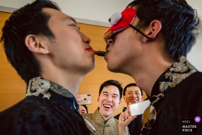 Zdjęcie: <a href="https://www.wpja.com/contests/2019-v12/best-wedding-photographers/2547431"> Will Tee - Taipei City </a> Sava Beach Villas Phuket Dzień ślubu Fotograf | Jeden z drużbów próbował nałożyć szminkę na drugiego drużba z maską na oku podczas sesji gier na drzwiach.