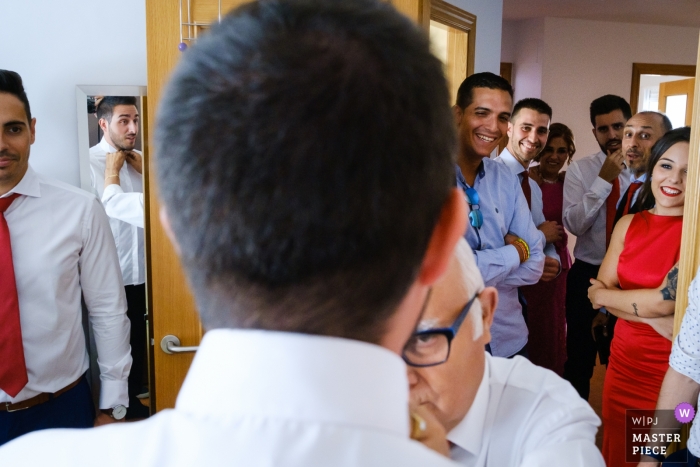 O noivo recebe ajuda com seus detalhes finais enquanto amigos e familiares assistem no dia do seu casamento em Alcoy. - casa novio, alcoy photography