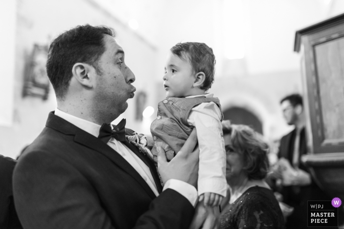 a man making faces at a little child Cuzion wedding photograph of a man making faces at a little child at church