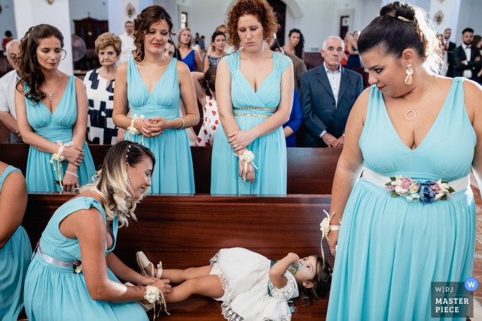 A dama de honra amarra os sapatos da florista durante uma cerimônia de casamento na Iglesia de Las Rozas.