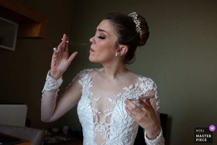 Foto von: <a href="https://www.wpja.com/contests/2019-v12/best-wedding-photographers/2548241"> Erkin Agsaran - Kadikoy Istanbul </a> Istanbul, Türkei Hochzeitsfotograf | Braut, die eine Zigarette raucht, um sich mit Telefon in ihrer Hand zu entspannen