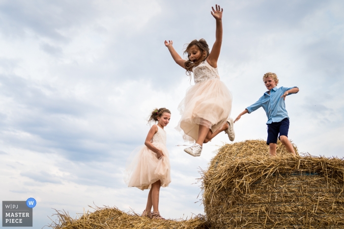 Fotografie op de locatie van de locatie - het huis van het bruidspaar. Bruidskinderen in het huwelijk genieten van balen stro door van tem springen.