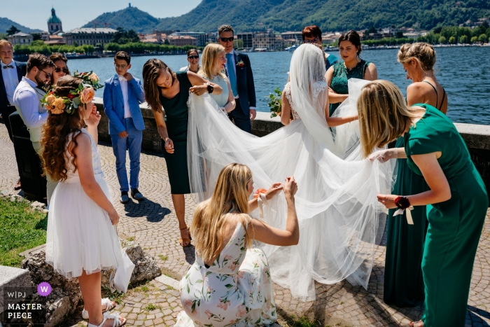 Photo by: <a href="https://www.wpja.com/contests/2019-v12/best-wedding-photographers/2548421">Leonard Walpot - Utrecht Utrecht</a> Netherlands outdoor wedding venue photo of bride with friends at the water fixing her dress