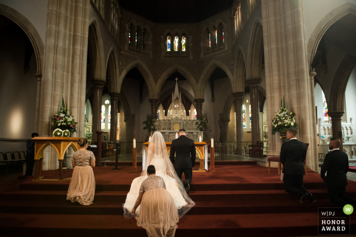 Before the prayer in church the bridesmaid helped the bride Victoria, Australia wedding photographer in Melbourne: Before the prayer, the bridesmaid helped the bride to arrange the skirt.