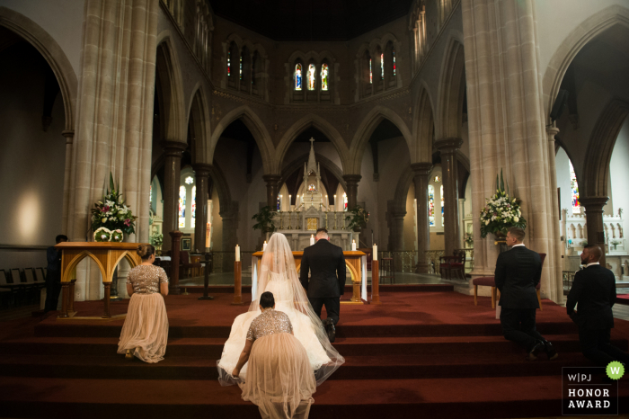 Victoria, Australia fotografo di matrimoni a Melbourne: prima della preghiera, la damigella d'onore ha aiutato la sposa a sistemare la gonna.