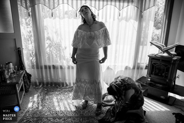 Fotografía del día de la boda de Holly's Ocean Meadow, Mendocino, CA | Imagen que muestra a la novia nerviosa preparándose mientras su mejor amigo ayuda con los zapatos