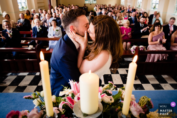 Dokumentarische Hochzeitsfotografie aus Waterville, Kerry, Irland | Erster Kuss für Braut und Bräutigam in einer überfüllten Kirche mit Familie und Freunden