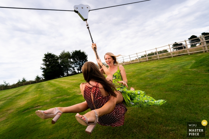 Photo by: <a href="https://www.wpja.com/contests/2019-v12/best-wedding-photographers/2548637">Tom Beynon - Cambridge Cambridgeshire</a> Wedding Reportage Photography at Skylark Farm, Warwickshire, UK - Image of female Guests enjoy the zipwire at the outdoor reception on the lawn.
