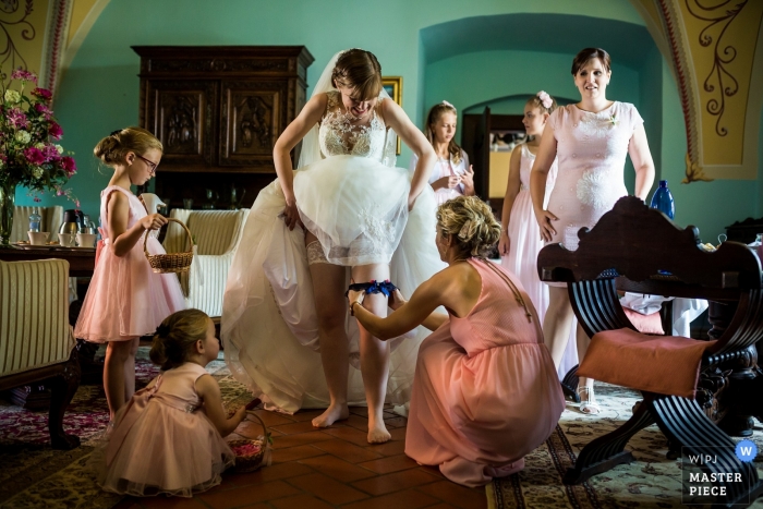 Photo by: <a href="https://www.wpja.com/contests/2019-v12/best-wedding-photographers/2548676">Matouš Bárta - Prague </a> Wedding Photography from the Chateau Valeč - Installing the garter for the bride while getting ready.