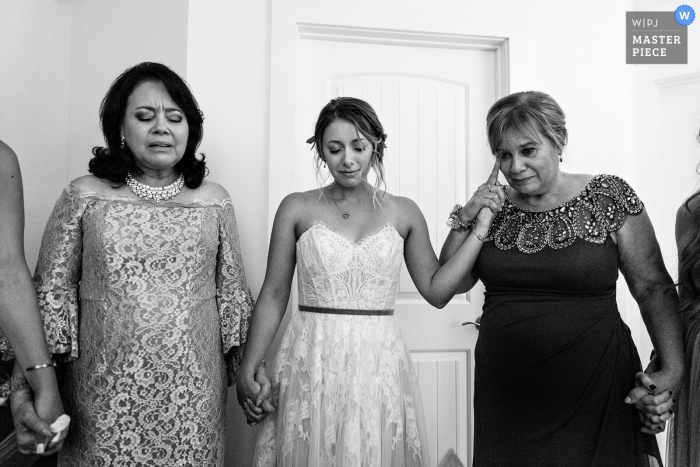 Photo by: <a href="https://www.wpja.com/contests/2019-v12/best-wedding-photographers/2548805">Kate Crabtree - Bangor Maine</a> Lamoine, Maine Wedding Photography - A mother of the bride cries as she prays with her daughter and her daughter's future mother in law.