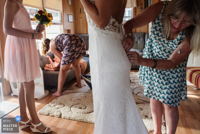 Foto: <a href="https://www.wpja.com/contests/2019-v12/best-wedding-photographers/2548842"> Meg Brock - Holland Pennsylvania </a> Seebrise New-Jersey, welches die bereite Hochzeitsphotographie zeigt das Kleid der Braut geknöpft erhält