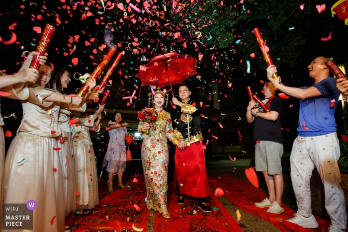 Photo by: <a href="https://www.wpja.com/contests/2019-v12/best-wedding-photographers/2548870">Di Liu - Hangzhou </a> Dongguan, China actual day wedding photography of the bride and groom - back to home under red umbrella and confetti cannons